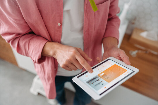 Man using smart thermostat, adjusting, lowering heating temperature at home. Concept of smart technology and thermostats in home.