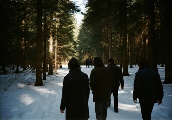 People walking in snowy forest path surrounded by trees