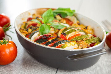 prepared baked zucchini and tomatoes in circles in a ceramic form, vegetable snack