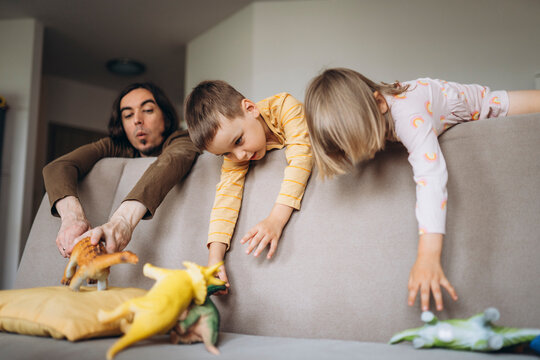 Father and children playing on sofa in living room at home