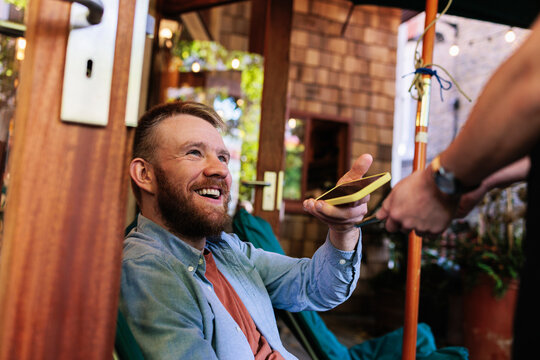 Happy man paying through smart phone at coffee shop