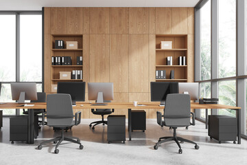 Fototapeta premium Workplace interior with armchairs and desks, pc monitors and shelf near window