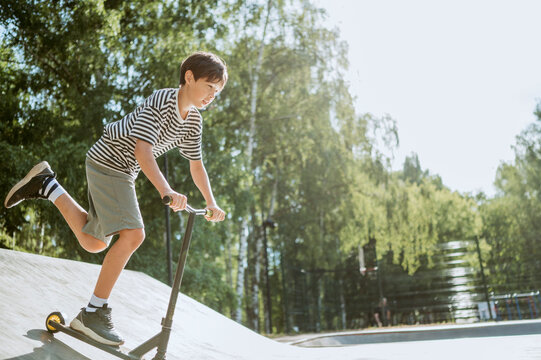 Pre-adolescent boy riding push scooter on sunny day