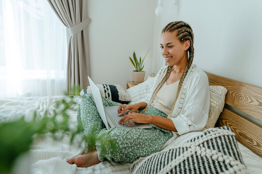 Happy freelancer working on laptop in bedroom at home