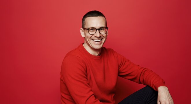 Smiling man in red sweater against vibrant red background