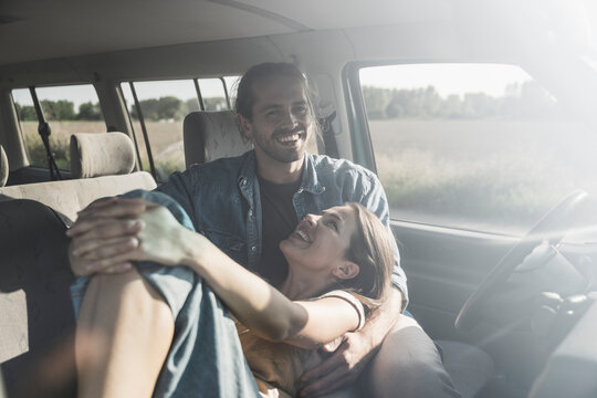 Happy loving couple spending time together in car on sunny day