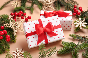 Christmas tree branches with gift boxes, rowan and decorations on beige background