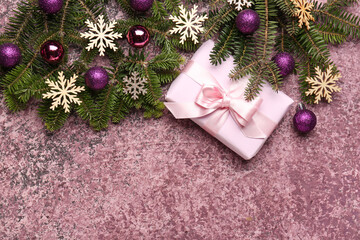 Christmas tree branches with balls, snowflakes and gift box on purple background