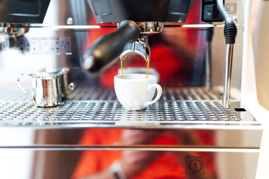 Espresso shot pouring in cup at coffee shop