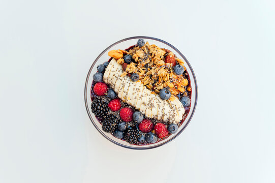 Healthy yogurt bowl of muesli with fruits and chia seeds over white background