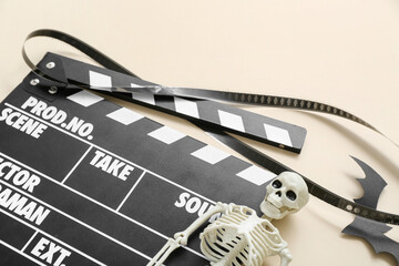 Clapperboard with film reel and Halloween decor on beige background