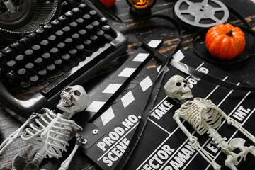 Typewriter with clapperboard, film reel and Halloween decor on black wooden background