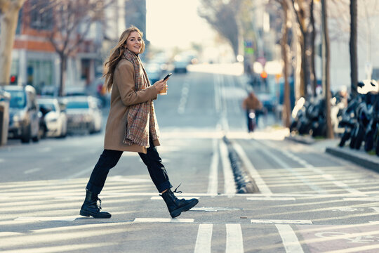 Smiling woman crossing road at crosswalk