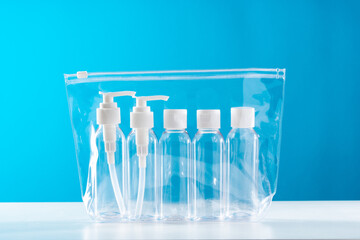 Transparent toiletry bag containing various travel-sized containers on a bright blue background