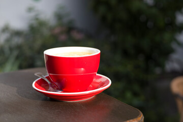 Red cup with aromatic coffee on wooden table, closeup