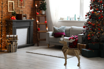 Interior of festive living room with wooden deer, Christmas tree and fireplace
