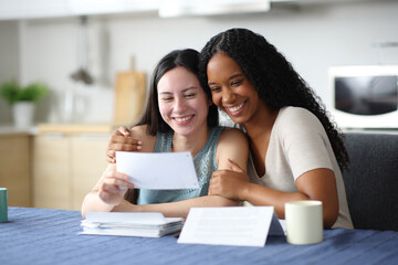 Happy interracial lesbian couple or friends checking receipt