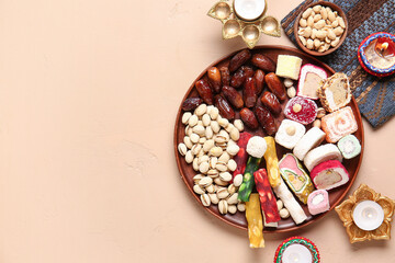 Diya lamps with candles and plates of different treats on beige background. Divaly celebration