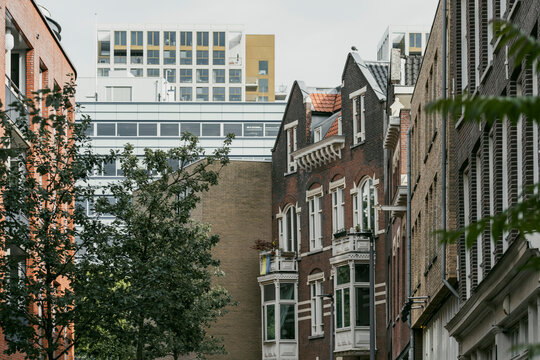 This image depicts a charming street that combines modern and historic architectural styles, with classic brick buildings and sleek, contemporary structures in the background.