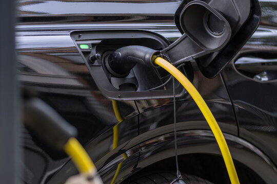 The image focuses on an electric vehicle being charged, highlighting sustainable transportation solutions and the growing adoption of eco-friendly technologies in urban areas.