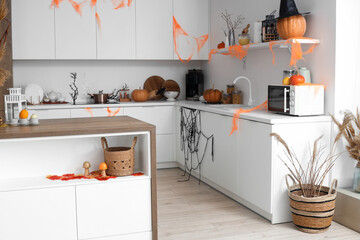 Interior of light kitchen decorated for Halloween with white counters