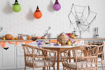 Interior of light kitchen decorated for Halloween with counters and dining table