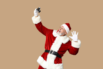 Shocked Santa Claus in glasses with camera taking photo on brown background