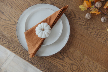 Autumn-inspired table setting with a pumpkin and napkin arrangement on wooden table