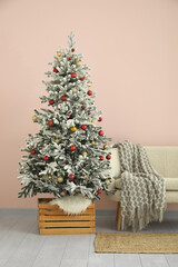 Beautiful Christmas tree with sofa near pink wall