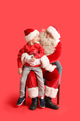 Santa Claus and cute little boy on red background