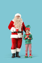 Santa Claus and cute little elf with cups of hot chocolate on blue background