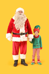 Santa Claus and cute little elf holding hands on yellow background