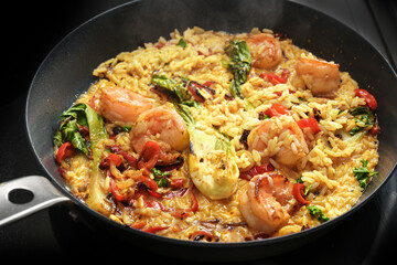 Curry rice pan with shrimps and vegetables, cooking a rustic homemade meal, selected focus