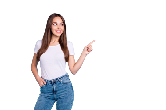 Portrait of pretty youth pointing at copy space looking at ads wearing white t-shirt denim jeans isolated over blue background