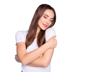 Portrait  of lovely girl cuddling herself with closed eyes wearing white t-shirt isolated over blue background