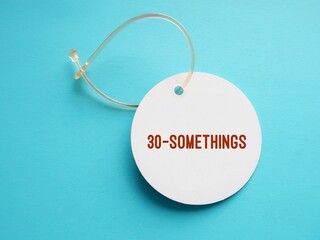 Luggage tag on blue background with text words 30 SOMETHINGS - unspecified age in thirties - person age between 30 and 39