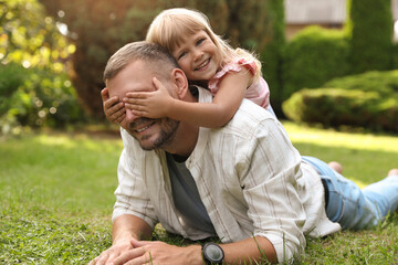 Father and his daughter spending time together on green lawn in park