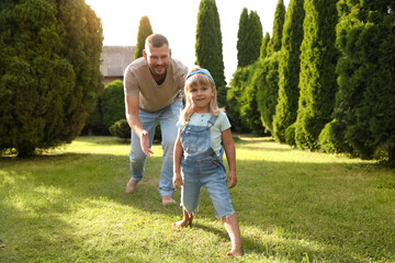 Fototapeta premium Father and his daughter spending time together on green lawn in park