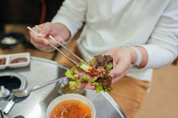 A Korean man and a Japanese woman, both in their 30s and a married couple, are enjoying a meal of Samgyeopsal at a famous restaurant in Jung District, Seoul, Korea, on an autumn night in October.