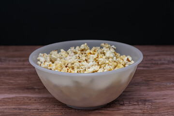 A bowl of popcorn is sitting on a wooden table