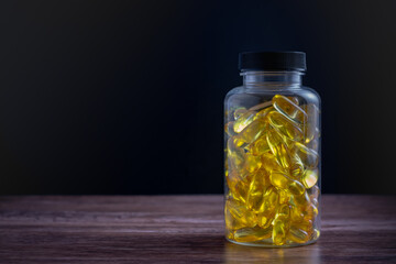 A bottle of fish oil pills sits on a wooden table