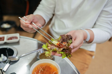 A Korean man and a Japanese woman, both in their 30s and a married couple, are enjoying a meal of Samgyeopsal at a famous restaurant in Jung District, Seoul, Korea, on an autumn night in October.