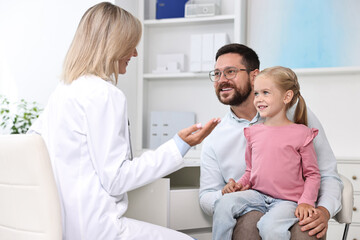 Fototapeta premium Doctor consulting little girl and her father in hospital