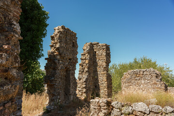 historic ruins of old houses made of stones, surrounded by vegetation