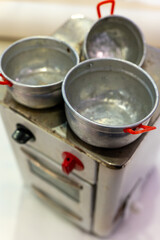 Three aluminum pots with red handles sit on a vintage stovetop