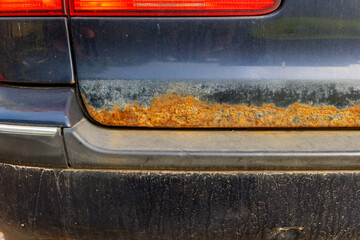 A close-up view of a car's rear bumper showing significant rust damage