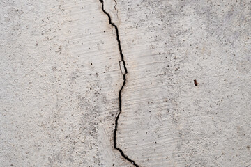 Cracked concrete wall showing a deep fracture and rough textured surface, highlighting imperfections in the material.
