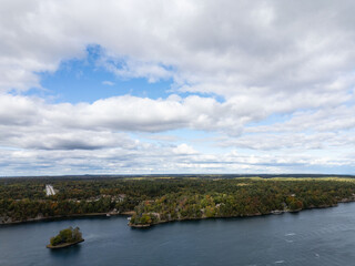 Scenic aerial view near the 1000 Islands Bridge, capturing the lush islands and waterways of the 1000 Islands region. A peaceful blend of green foliage and open water stretches under a cloudy sky