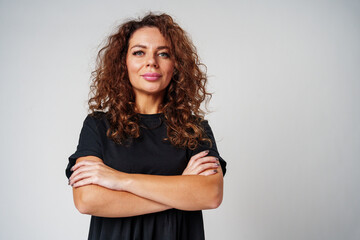 Confident woman with curly hair posed against a neutral background