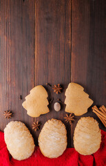 Homemade Christmas cookies in the shape of a cedar cone and a Christmas tree with spices on a wooden background with copy space.